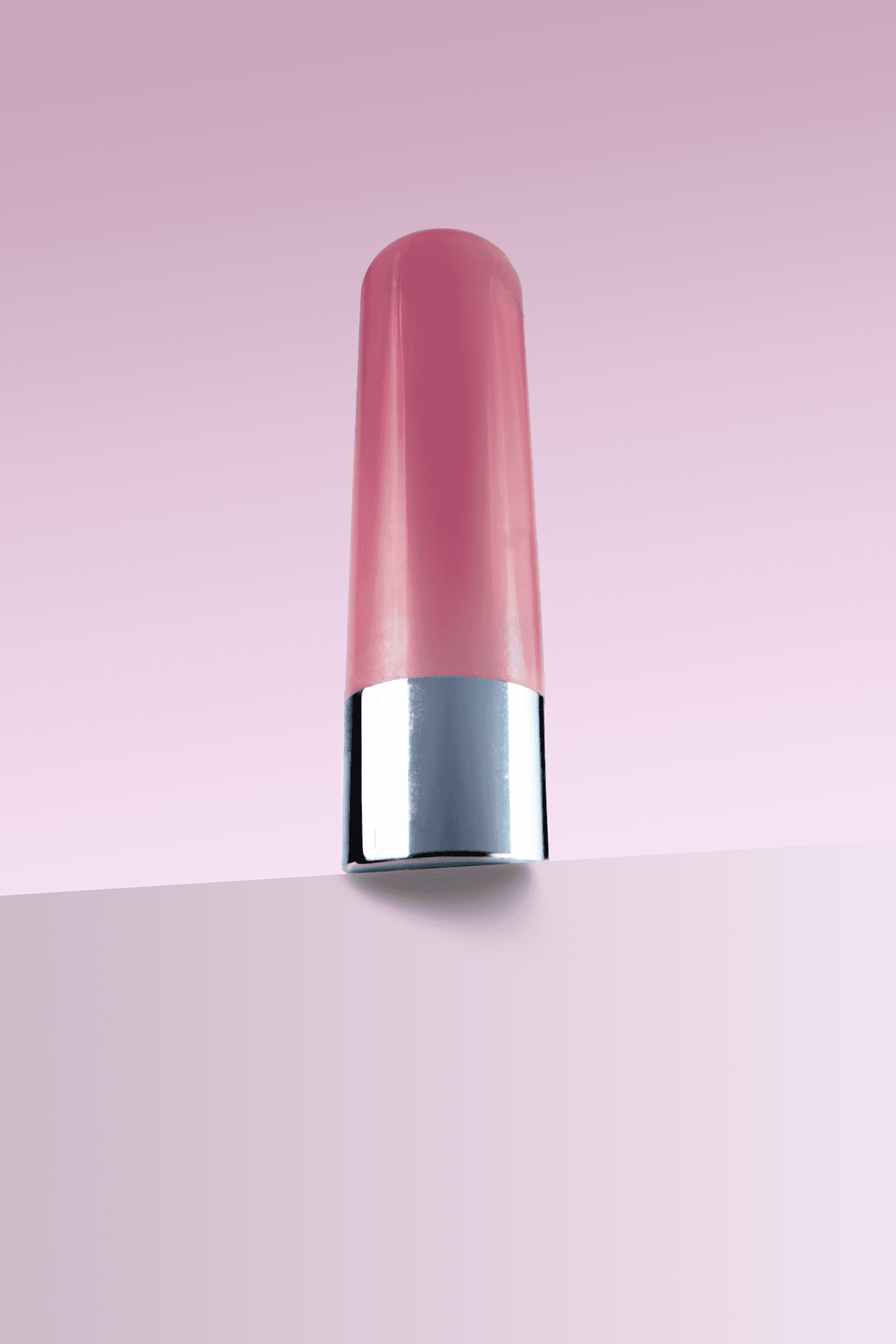 Petal Lip Tint in a rose-pink tube standing upright against a soft pink gradient background.